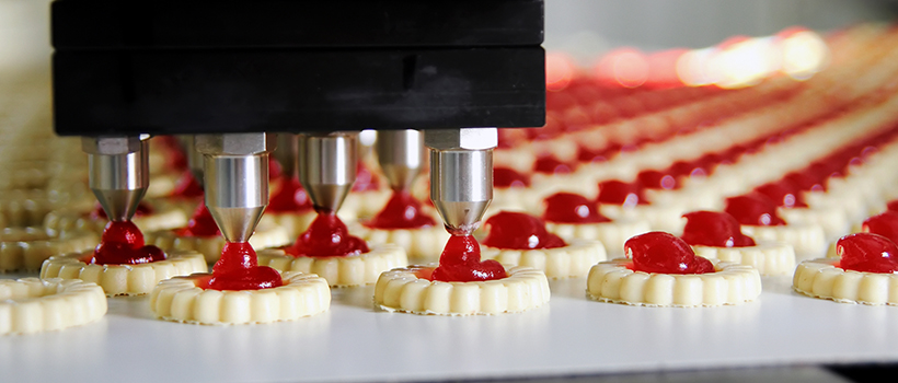 Biscuits having red jelly jam piped on food production line