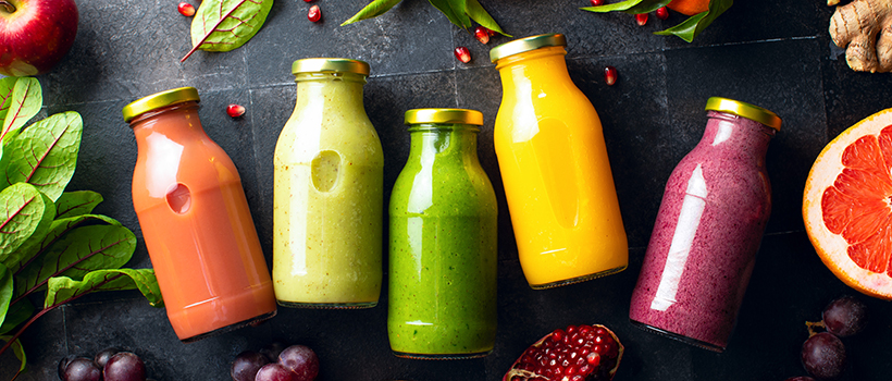 Selection of smoothie drinks in glass bottles with surrounding fruit