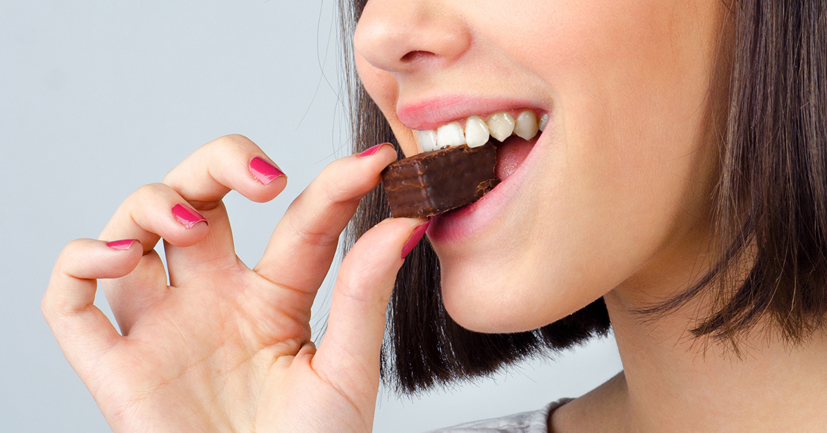 Young woman biting into chocolate treat
