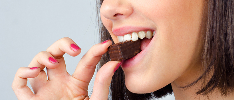 Woman biting a small chocolate
