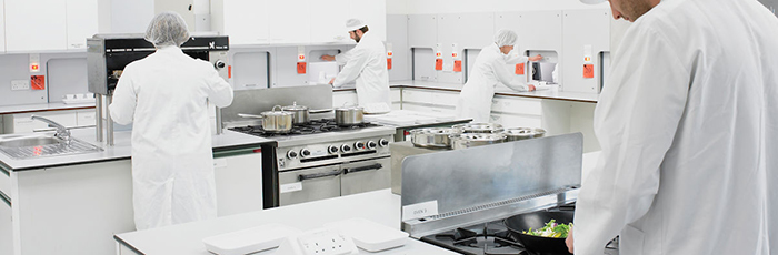 Employees working in sensory kitchen, cooking and passing food into booths