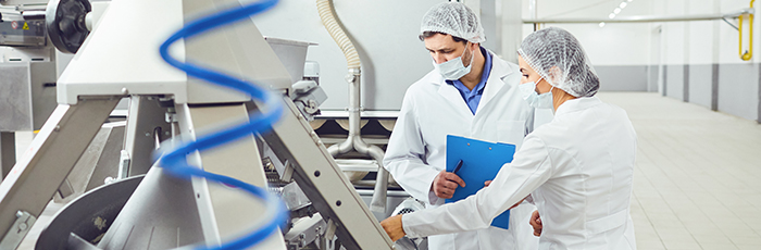 Man and woman inspecting equipment at a food factory