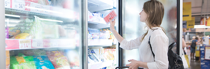 Shopper selecting food from a supermarket freezer
