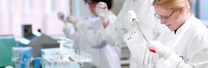 Scientists in laboratory testing with pipettes