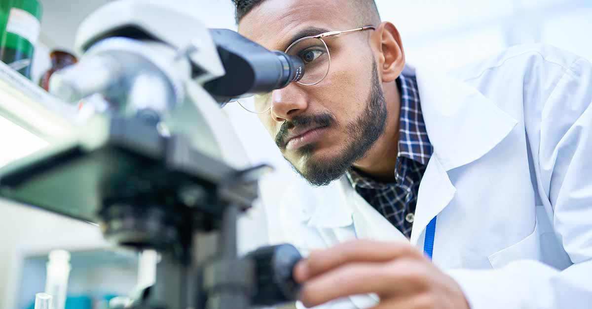 Microbiologist looking through microscope