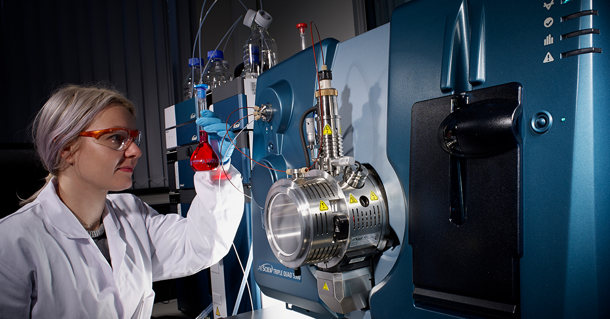 Scientist looking at flask using laboratory equipment