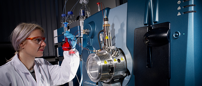 Scientist looking at flask using laboratory equipment