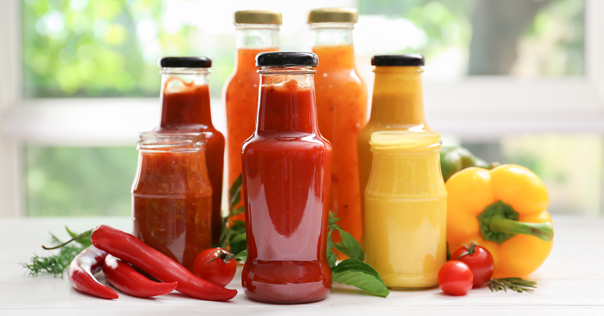 Selection of vegetables surrounding sauce jars