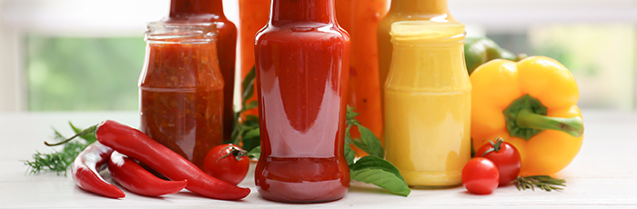 Selection of vegetables surrounding sauce jars