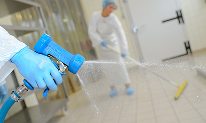 Factory workers cleaning factory with water hose